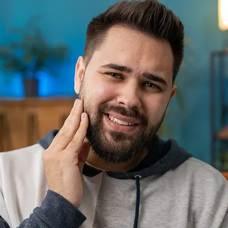 A man holding his jaw, indicating tooth pain